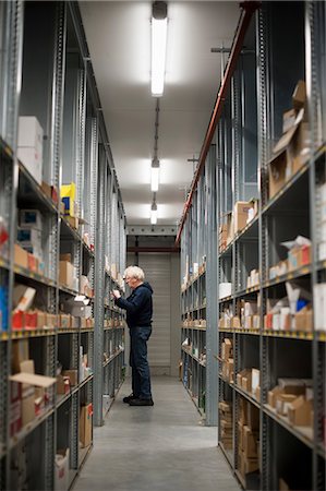 simsearch:614-06624509,k - Male warehouse worker selecting item from shelving Photographie de stock - Premium Libres de Droits, Code: 649-06829909