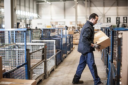 simsearch:649-07239387,k - Male warehouse worker lifting cardboard box onto distribution trolley Stock Photo - Premium Royalty-Free, Code: 649-06829901