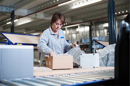 shipping package - Female warehouse worker packing box for conveyor belt Stock Photo - Premium Royalty-Free, Code: 649-06829920