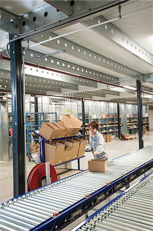 simsearch:6113-07160274,k - Female warehouse worker placing box onto conveyor belt Stock Photo - Premium Royalty-Free, Code: 649-06829922