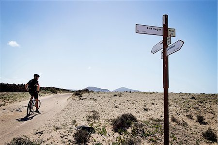 panneau de signalisation - Man mountain biking past sign post, Lanzarote Photographie de stock - Premium Libres de Droits, Code: 649-06829975