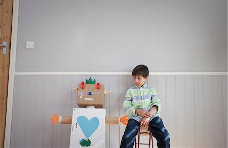 Boy sitting next to homemade toy robot Stock Photo - Premium Royalty-Free, Code: 649-06830154