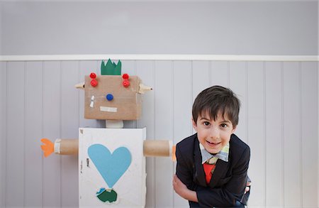 Boy leaning towards camera with homemade toy robot Stock Photo - Premium Royalty-Free, Code: 649-06830155