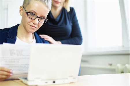 Businesswoman with paperwork with colleague's hand on shoulder Stock Photo - Premium Royalty-Free, Code: 649-06830157