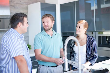 Young couple with salesman in kitchen showroom Foto de stock - Sin royalties Premium, Código: 649-06844111