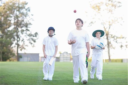 simsearch:649-06844269,k - Three boys walking on cricket pitch Fotografie stock - Premium Royalty-Free, Codice: 649-06844268