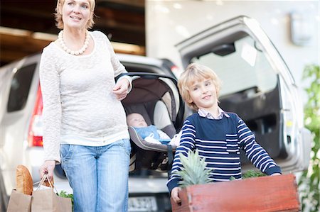 Mother with baby car seat and son carrying box of plants Photographie de stock - Premium Libres de Droits, Code: 649-06844306
