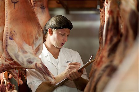 Butcher with clipboard inspecting meat Fotografie stock - Premium Royalty-Free, Codice: 649-06844338