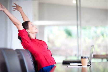 Young woman in office stretching Stock Photo - Premium Royalty-Free, Code: 649-06844373