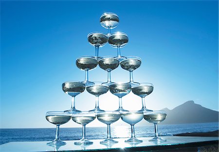 simsearch:649-06844312,k - Champagne glasses in pyramid shape with sea in background Foto de stock - Royalty Free Premium, Número: 649-06844406