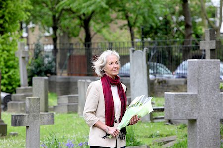 sad 60 year old people - Senior woman holding flowers in graveyard Stock Photo - Premium Royalty-Free, Code: 649-06844550