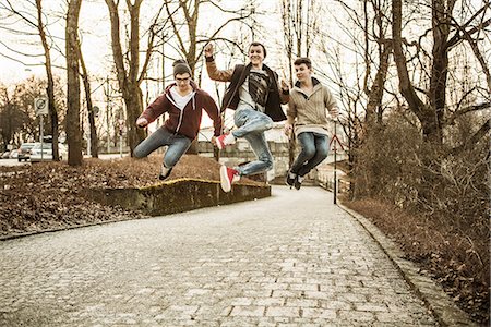 simsearch:649-06844592,k - Three teenage boys jumping in park Photographie de stock - Premium Libres de Droits, Code: 649-06844592