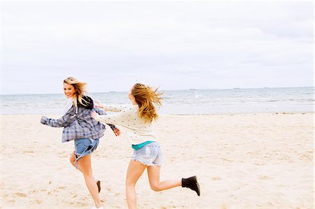 Girlfriends playing chasing game on the beach Stock Photo - Premium Royalty-Free, Code: 649-06844675