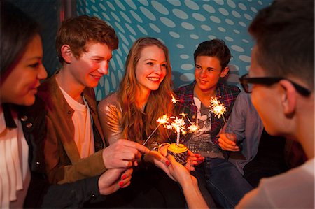 simsearch:649-06844687,k - Group of teenagers sitting around birthday cake with sparklers Foto de stock - Sin royalties Premium, Código: 649-06844693