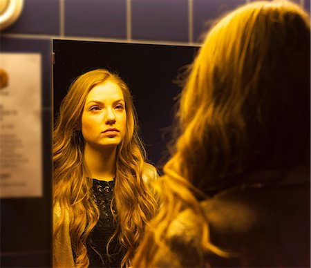 Teenage girl looking at her reflection in mirror Stock Photo - Premium Royalty-Free, Code: 649-06844717