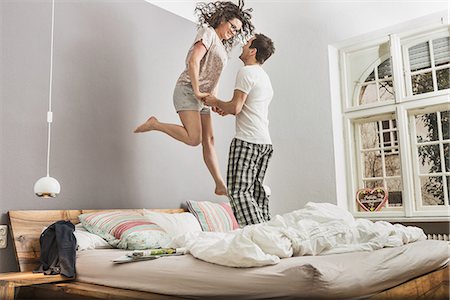 simsearch:649-06844779,k - Mid adult couple wearing pyjamas jumping on bed Foto de stock - Sin royalties Premium, Código: 649-06844748