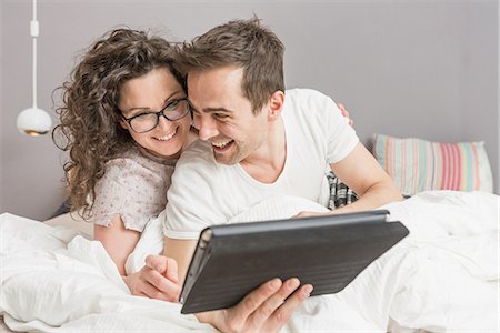 Mid adult couple lying on bed using digital tablet Photographie de stock - Premium Libres de Droits, Code: 649-06844760