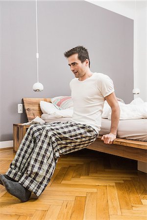 pyjamas (sleepwear with pants) - Mid adult man wearing pyjamas doing exercise on bed Stock Photo - Premium Royalty-Free, Code: 649-06844771