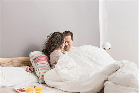 Mid adult couple lying in bed, breakfast on tray Stock Photo - Premium Royalty-Free, Code: 649-06844772