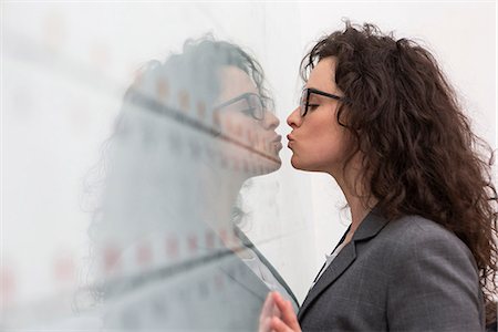 Businesswoman kissing her reflection on wall Foto de stock - Sin royalties Premium, Código: 649-06844832