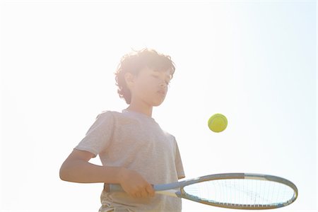 Boy bouncing ball on tennis racket Photographie de stock - Premium Libres de Droits, Code: 649-06844916