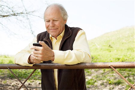 Senior man smiling at message on mobile phone Photographie de stock - Premium Libres de Droits, Code: 649-06844948