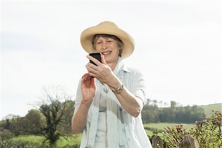 senior looking at phone - Senior woman smiling at message on mobile phone Stock Photo - Premium Royalty-Free, Code: 649-06844955