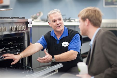 sales associate talking with customer - Young man and salesman in showroom Stock Photo - Premium Royalty-Free, Code: 649-07064069