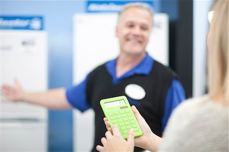 salesman with customer - Young woman with calculator in showroom Stock Photo - Premium Royalty-Free, Code: 649-07064076