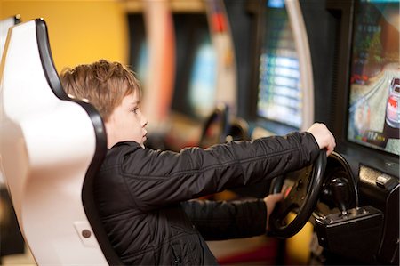 Boy playing on driving video game Foto de stock - Sin royalties Premium, Código: 649-07064101