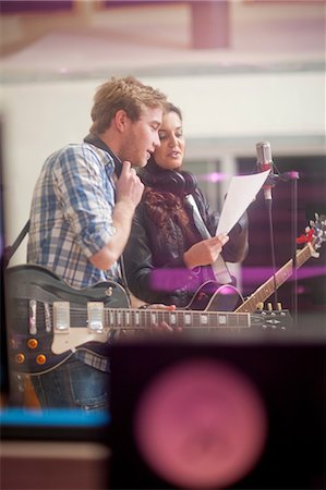 Young musicians looking at sheet of paper in recoding studio Stock Photo - Premium Royalty-Free, Code: 649-07064123