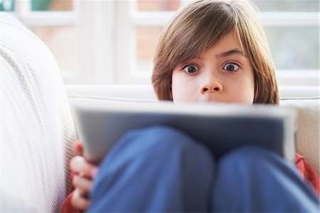 da solo - Boy on sofa using digital tablet Fotografie stock - Premium Royalty-Free, Codice: 649-07064237