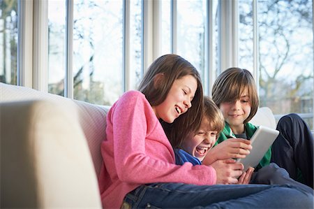 family laughing and relaxing on sofa - Siblings using digital tablet together Stock Photo - Premium Royalty-Free, Code: 649-07064274