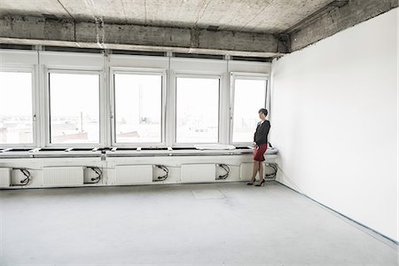 Businesswoman standing in empty unfinished office Stock Photo - Premium Royalty-Free, Code: 649-07064414