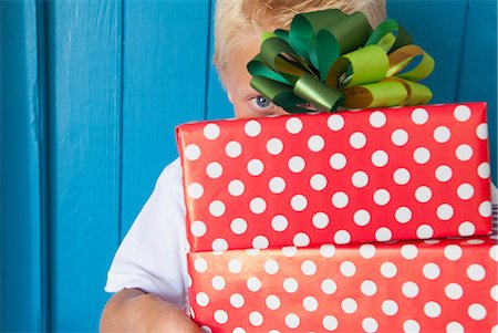 Boy peeping behind gifts in hand Stock Photo - Premium Royalty-Free, Code: 649-07064410