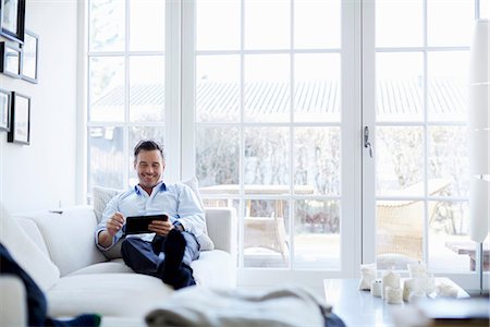 relax man in white - Man relaxing on sofa using digital tablet Stock Photo - Premium Royalty-Free, Code: 649-07064532