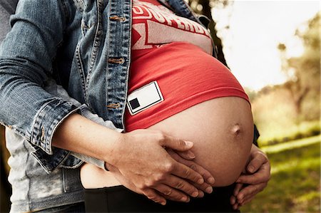 pregnant woman holding her stomach - Midsection of pregnant woman and partner holding bump Foto de stock - Sin royalties Premium, Código: 649-07064566