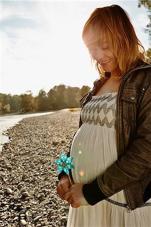 pregnant lady belly - Pregnant woman standing beside river holding windmill Foto de stock - Sin royalties Premium, Código: 649-07064572