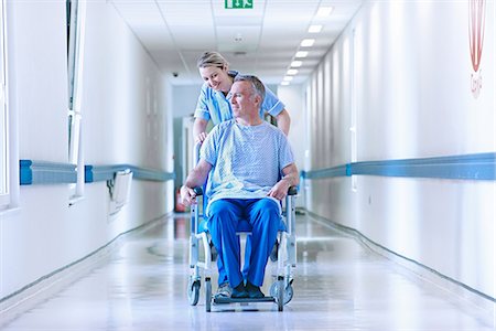 photo of a sick man in hospital - Nurse pushing patient in wheelchair down corridor Stock Photo - Premium Royalty-Free, Code: 649-07064709