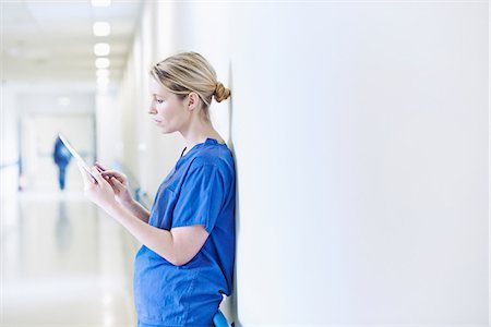 Doctor standing in corridor looking at digital tablet Photographie de stock - Premium Libres de Droits, Code: 649-07064722