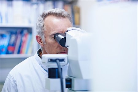 Man looking through microscope Stock Photo - Premium Royalty-Free, Code: 649-07064738