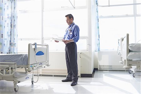 Doctor standing on hospital ward looking at medical records Photographie de stock - Premium Libres de Droits, Code: 649-07064756