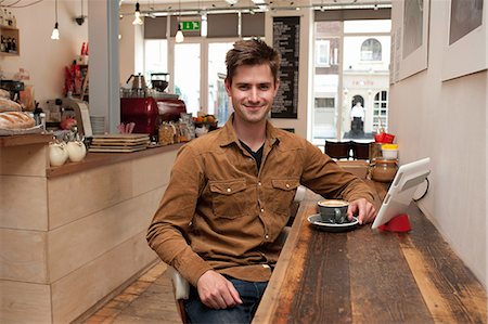 drinking coffe interior - Portrait of young man with coffee and digital tablet in cafe Foto de stock - Sin royalties Premium, Código: 649-07064892