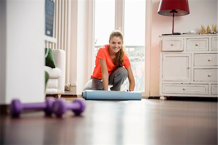 fitness home - Young woman rolling up exercise mat at home Foto de stock - Sin royalties Premium, Código: 649-07063025