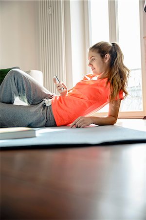 person looking at smart phone - Young woman using smartphone whilst lounging on floor Stock Photo - Premium Royalty-Free, Code: 649-07063029