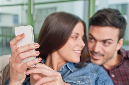 Young couple at home looking at mobile phone Fotografie stock - Premium Royalty-Free, Codice: 649-07063163