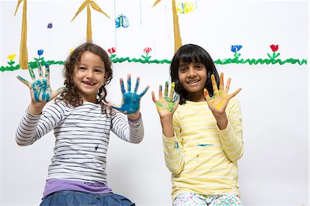 pintura a dedo - Two girls kneeling on floor with painted hands Foto de stock - Royalty Free Premium, Número: 649-07063448