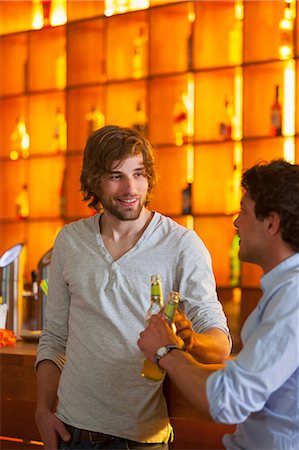 people drinking beer smiling - Two men standing at bar with bottles of beer Stock Photo - Premium Royalty-Free, Code: 649-07063515