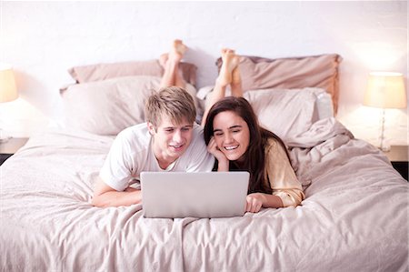 simsearch:649-07436595,k - Young couple lying on bed watching laptop Photographie de stock - Premium Libres de Droits, Code: 649-07063615