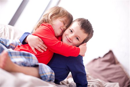 Two young children hugging on bed Stock Photo - Premium Royalty-Free, Code: 649-07063625